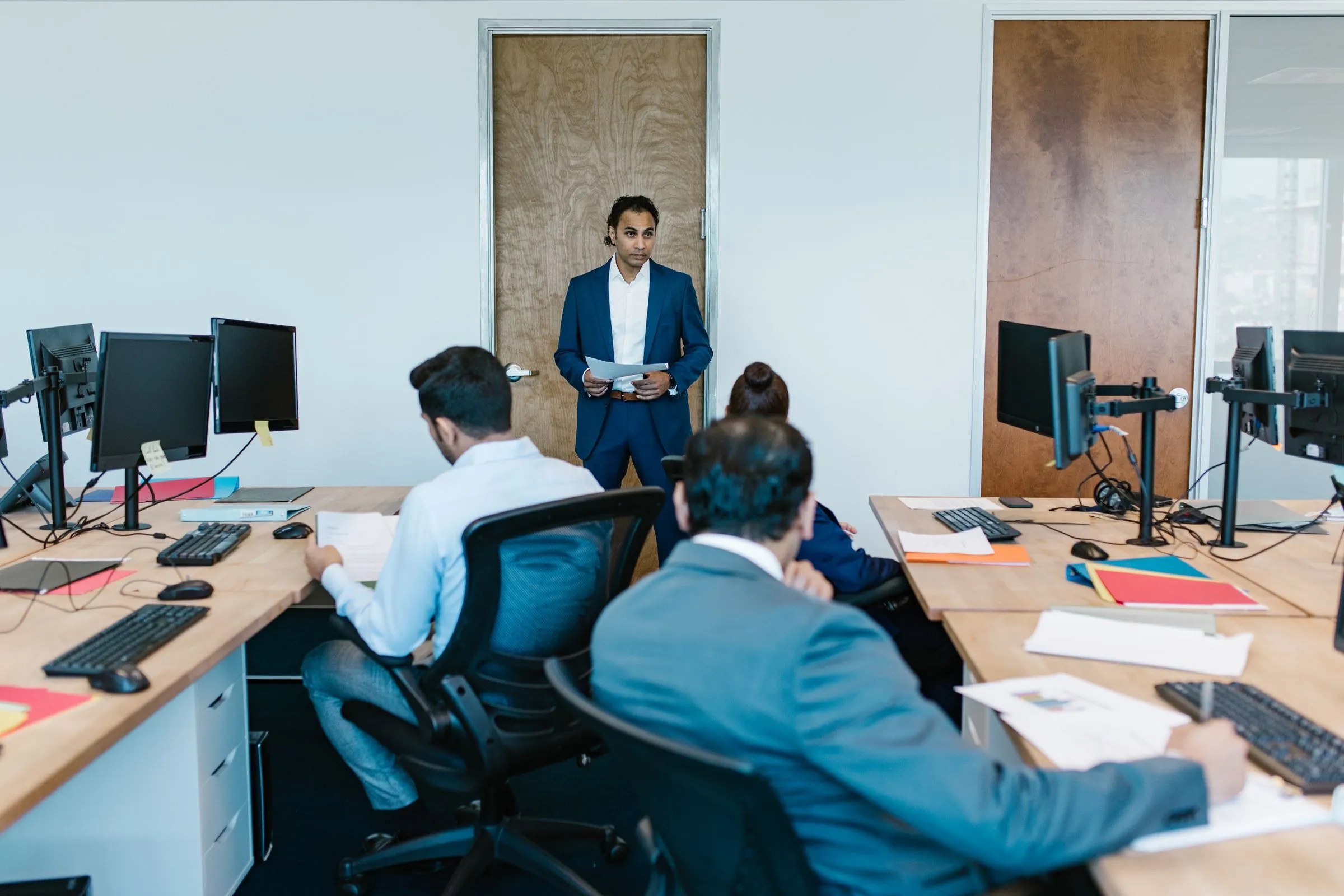 A team lead briefing colleagues at their desks